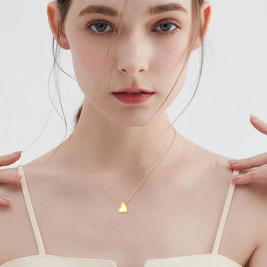 Model wearing an asymmetric 14K yellow gold heart pendant necklace.